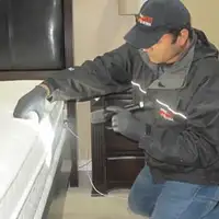 Bed bug inspection technician checking a mattress and bed frame for signs of infestation in Manchester, NH
