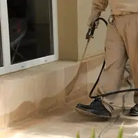General pest control technician spraying exterior perimeter around a home in Manchester, NH